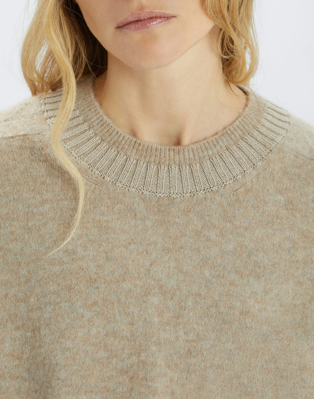 Close-up of a beige sweater with a ribbed neckline on a white background