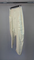 Light-colored pants with vertical stripes hanging on a rack against a gray background
