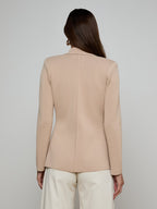 Person wearing a beige blazer against a plain background