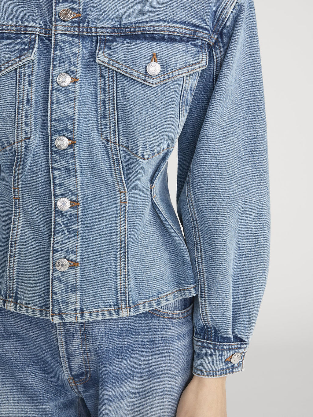 Close-up of a blue denim jacket with button details on a white background