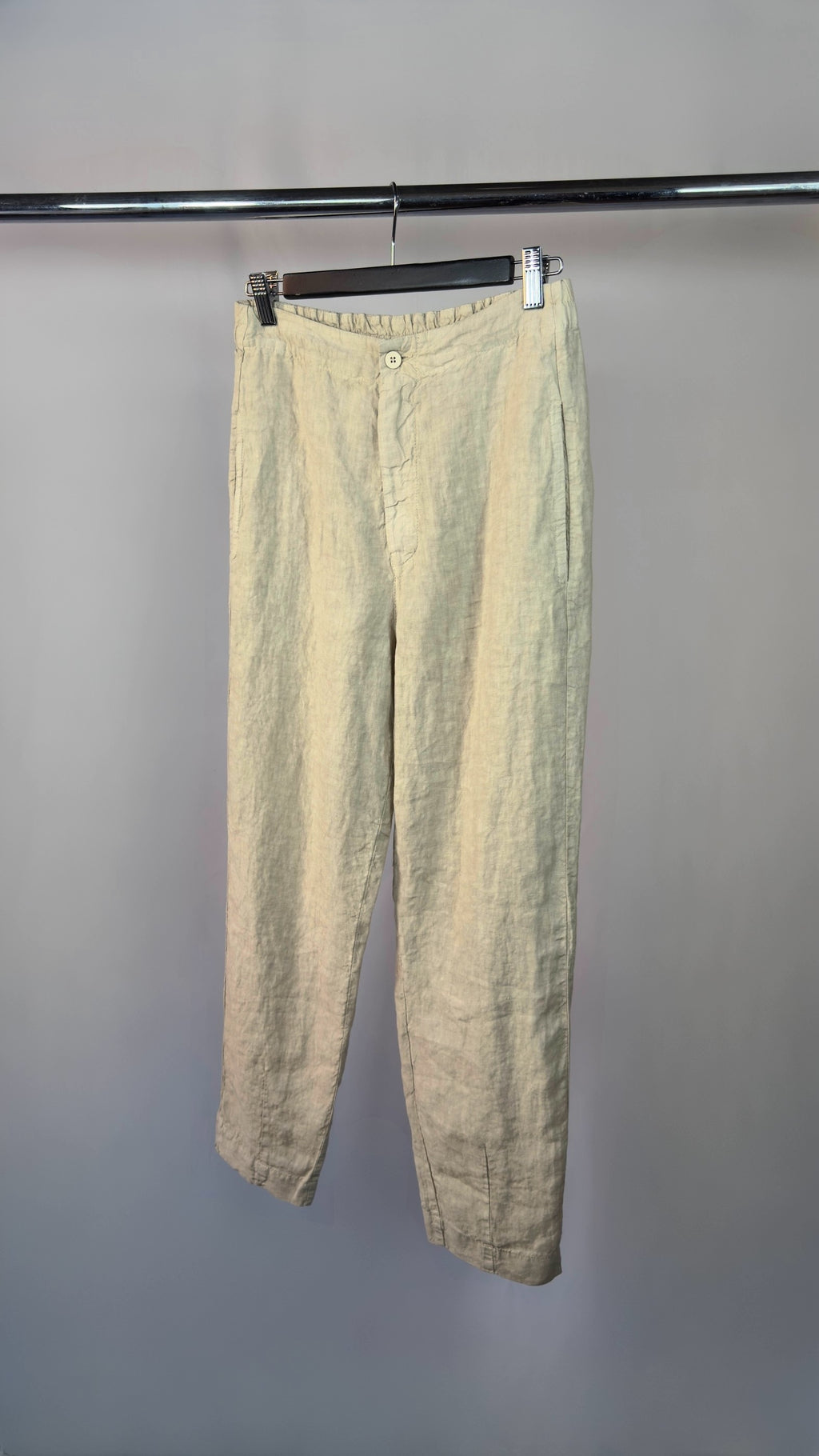 Light-colored pants hanging on a rack against a gray background