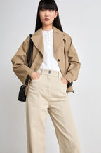 A woman modeling mid-rise, straight-leg beige cotton twill trousers with two front and two back pockets.
