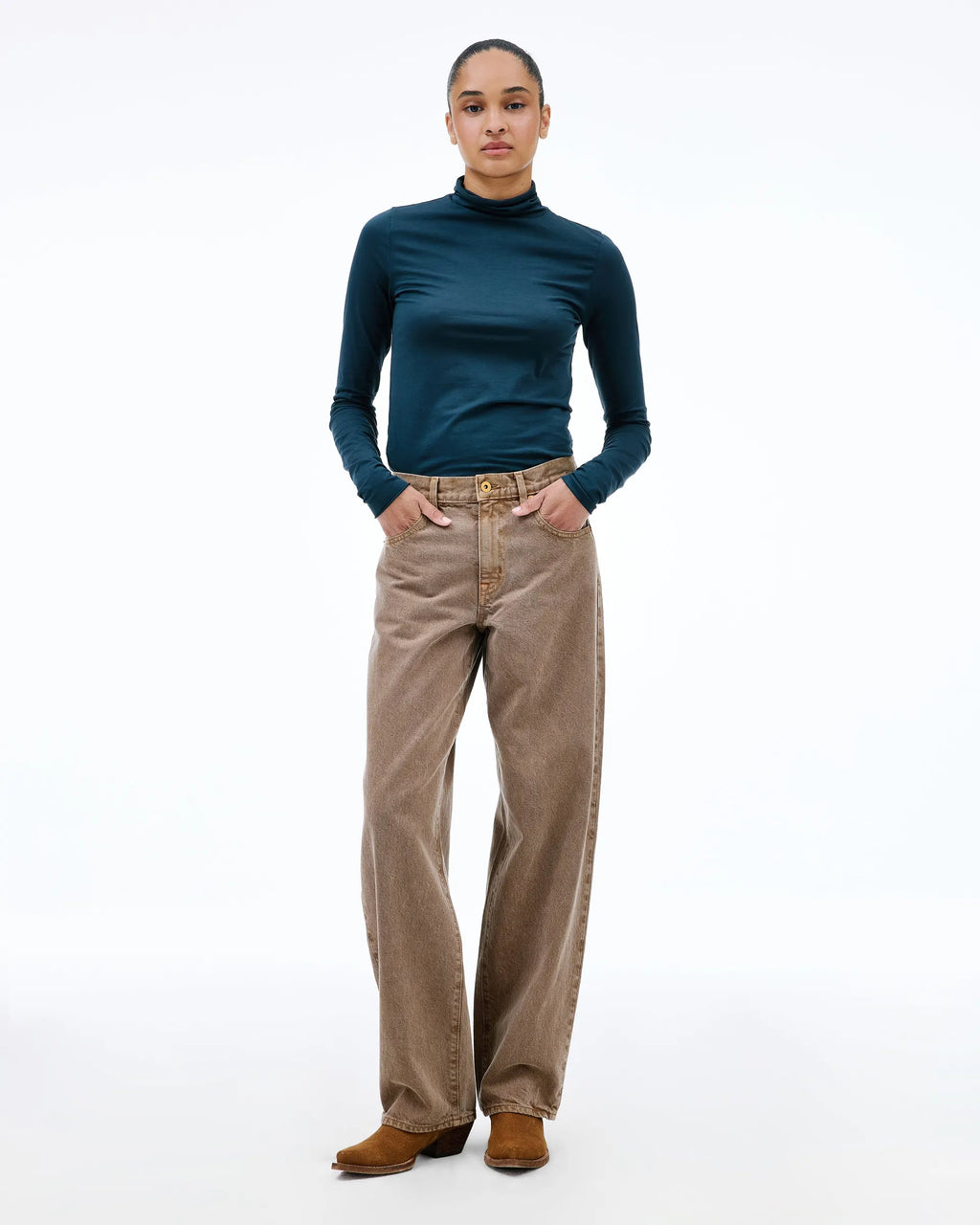 A model stands against a white studio background wearing a dark teal mock-neck long-sleeve top, high-waisted brown wide-leg corduroy pants, and brown suede boots.