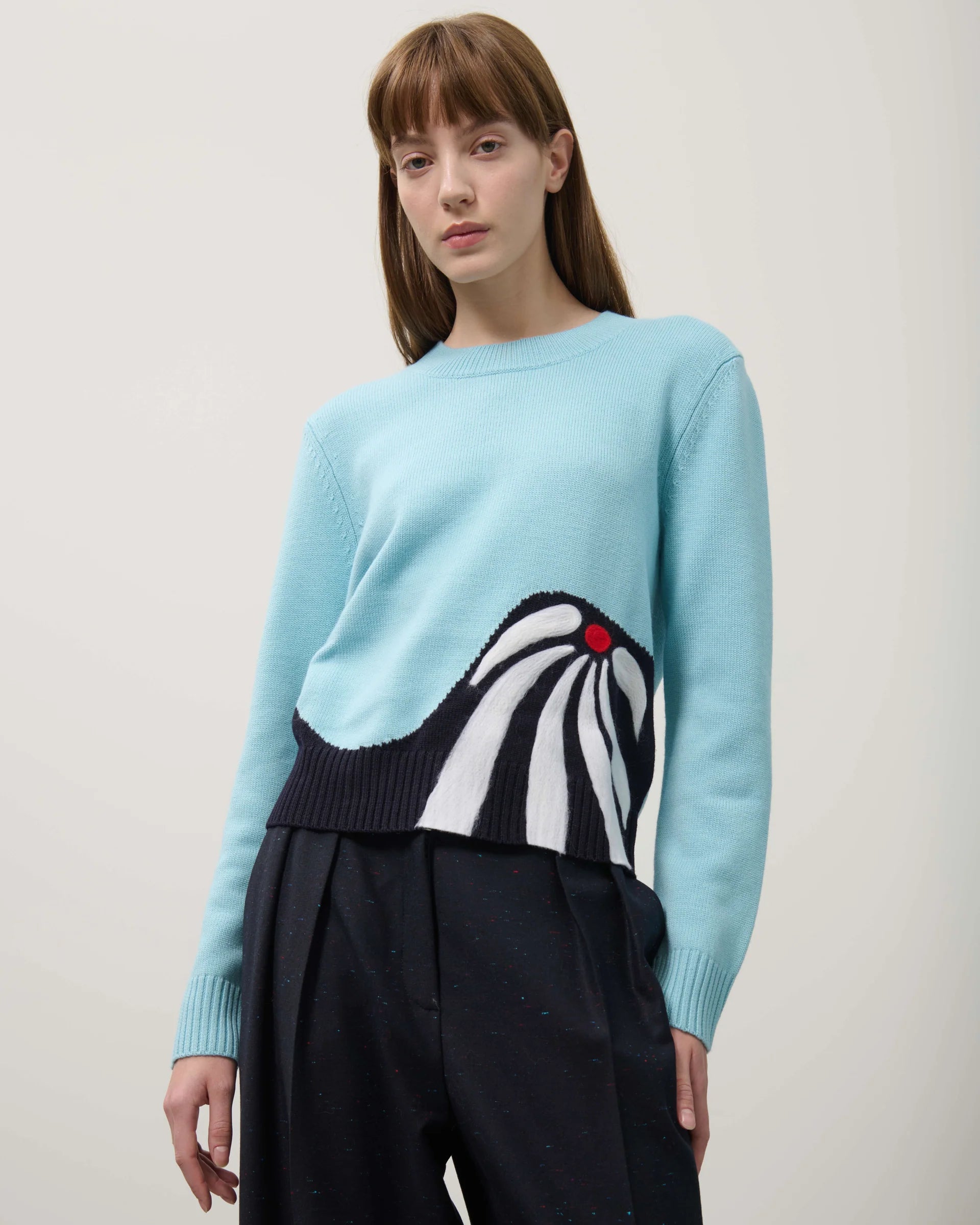 Person wearing a light blue sweater with a zebra design on a plain background