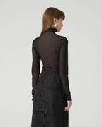 Woman wearing a black long-sleeve top and black lace skirt on a white background