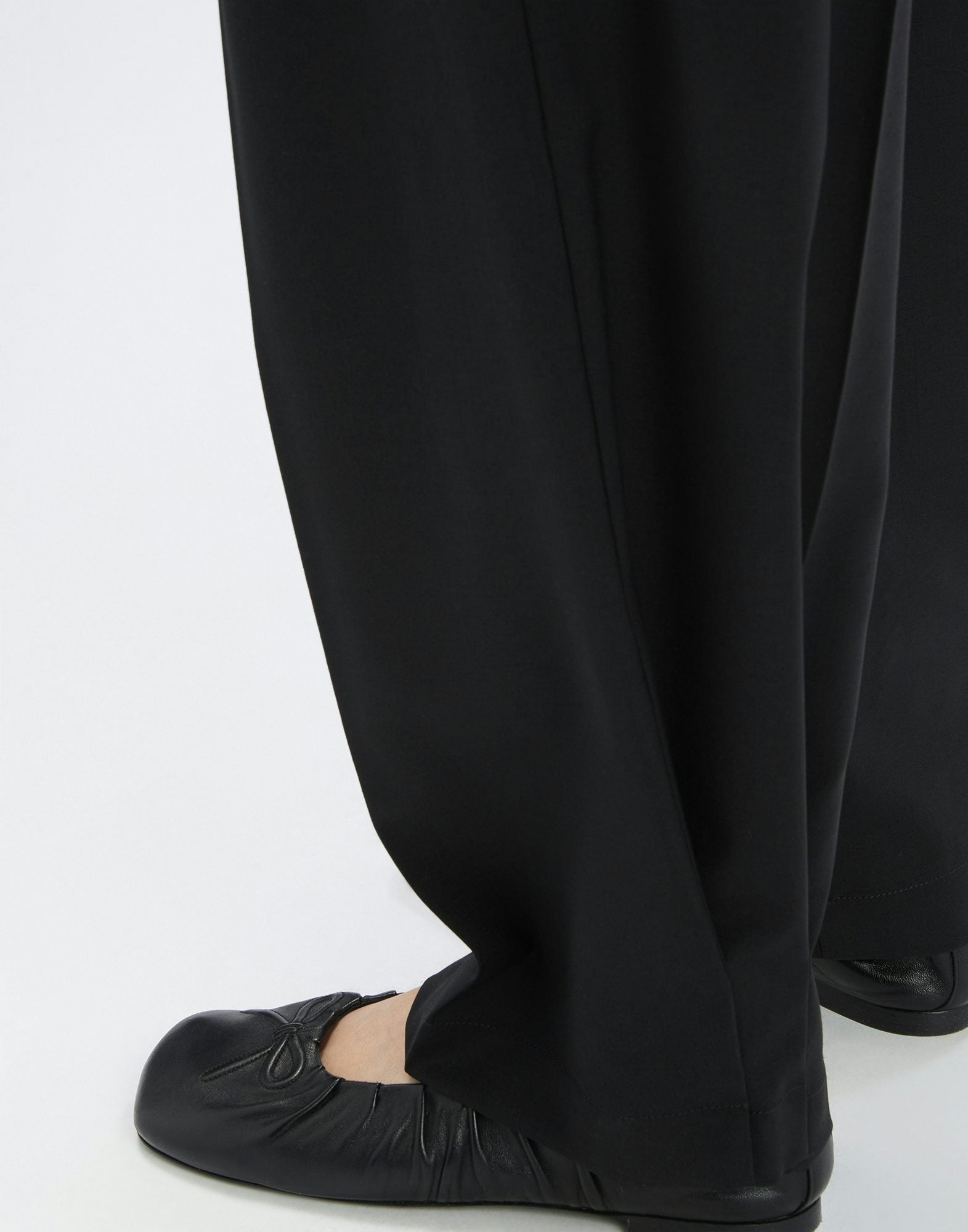 Black pants worn by a person on a white background