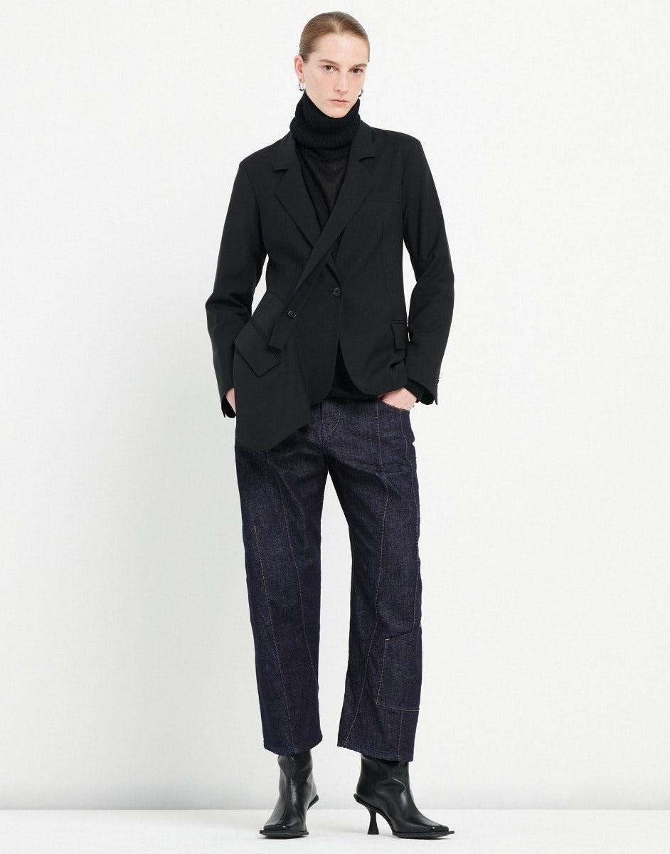 Person wearing a black coat, black turtleneck, and dark jeans on a white background