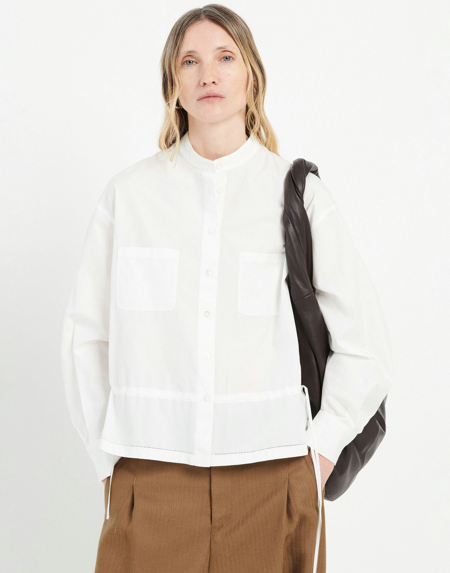 Person wearing a white shirt and brown pants with a black backpack on a white background