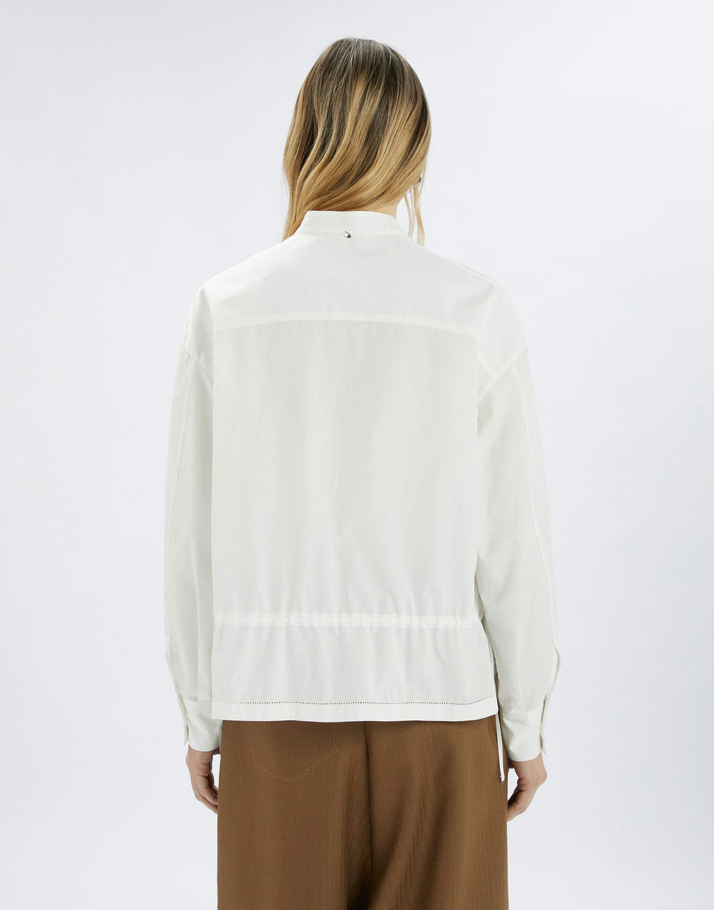 Person wearing a white blouse and brown pants on a white background