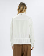 Person wearing a white blouse and brown pants on a white background