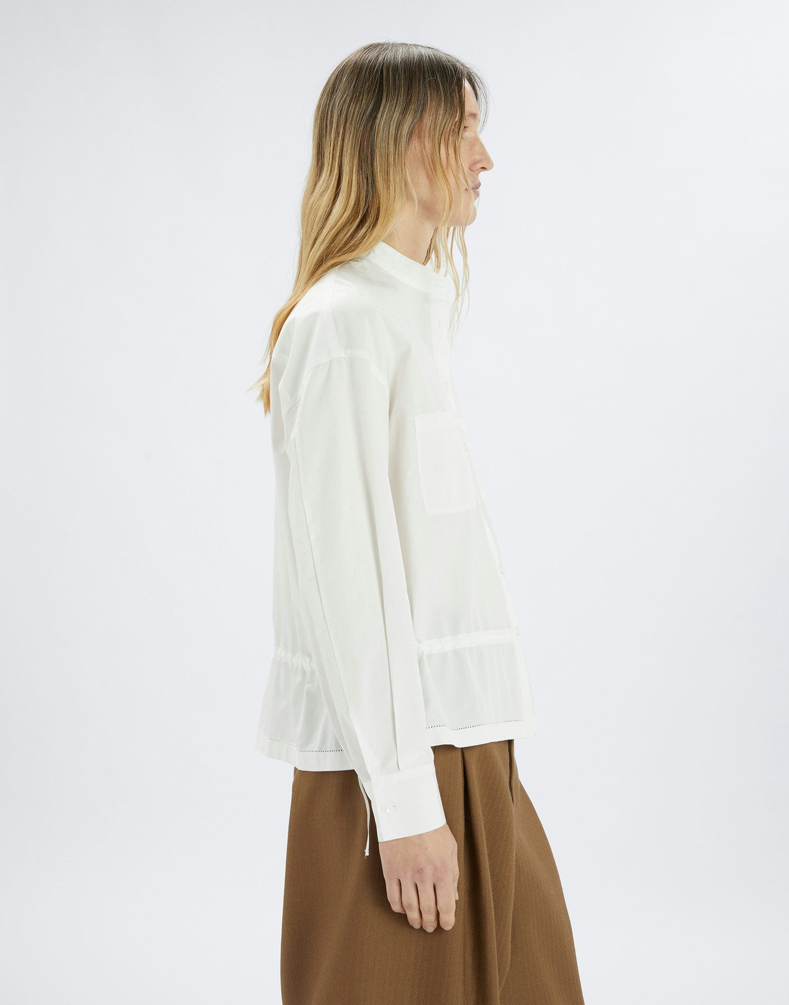 Woman wearing a white blouse and brown skirt on a white background