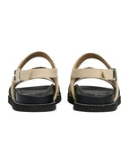 Pair of sandals with beige straps and black soles on a white background