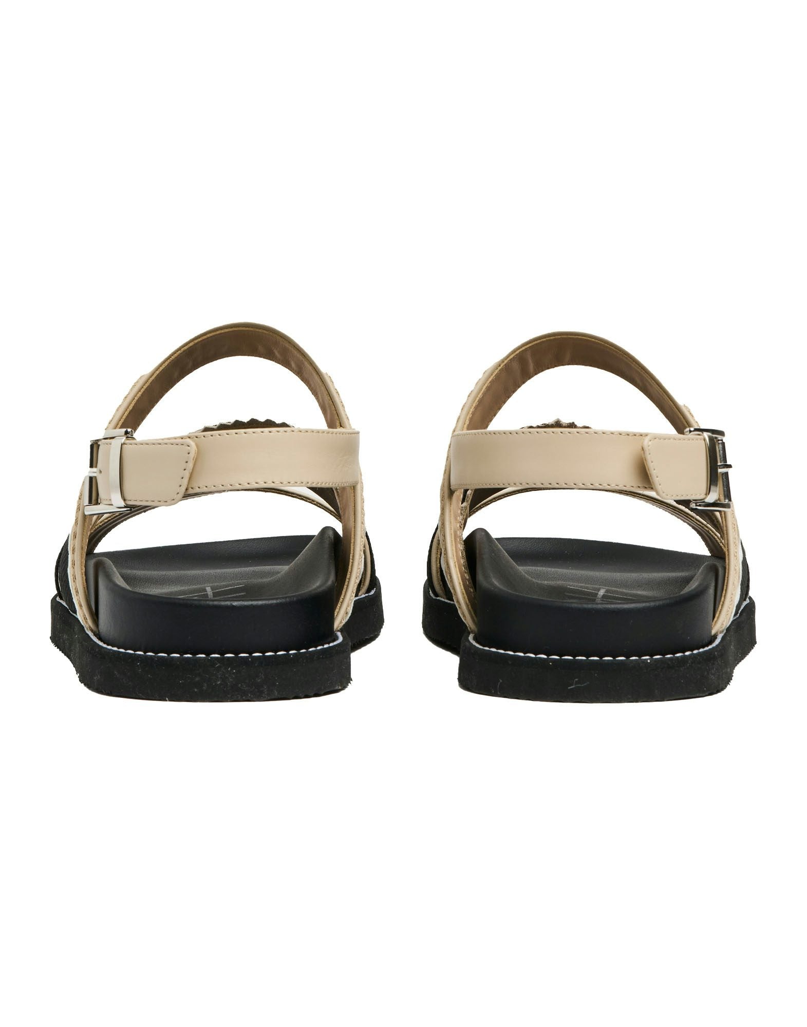 Pair of sandals with beige straps and black soles on a white background