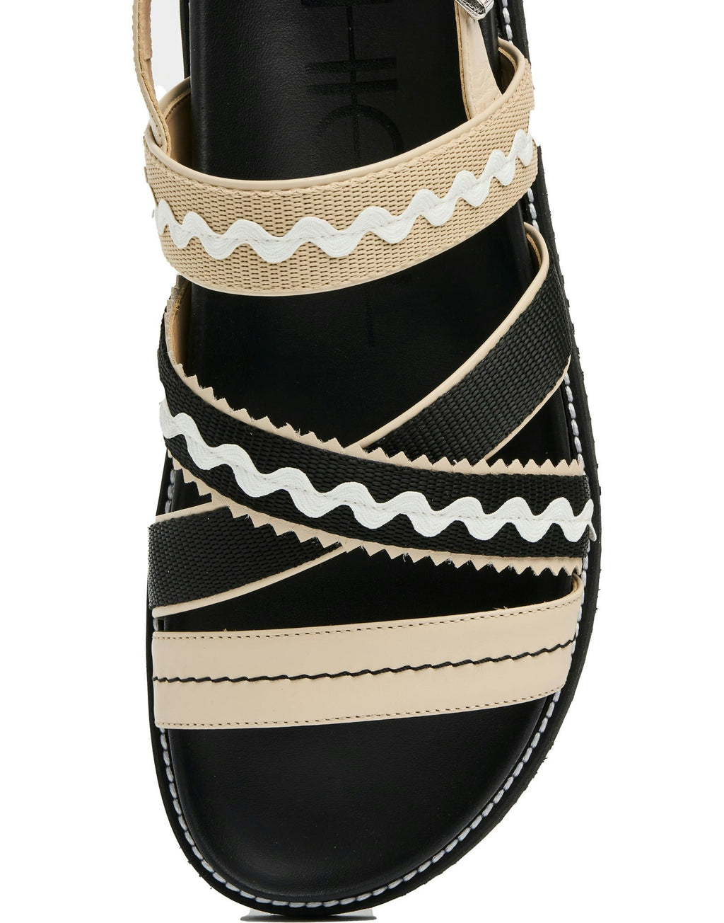 Black sandal with beige and white striped straps on a white background