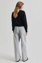 Person wearing a black sweater and light gray pants on a white background