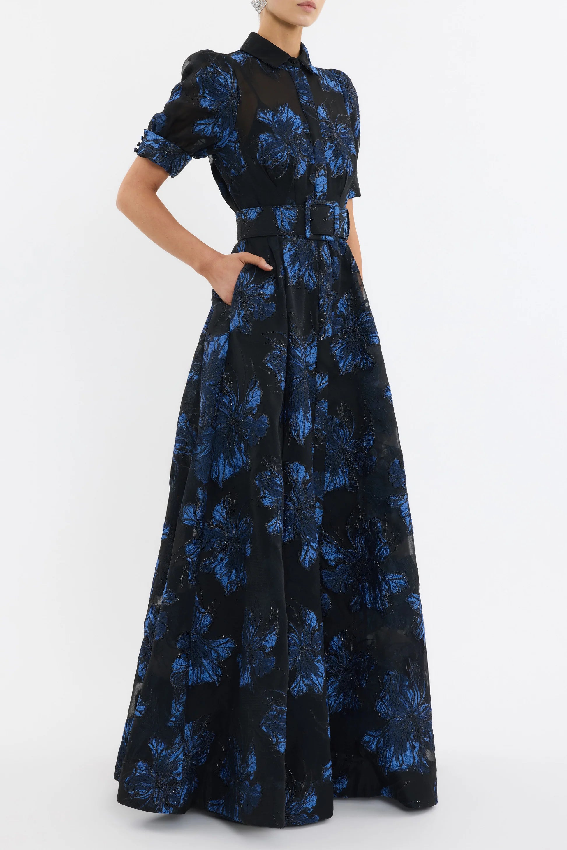 Black dress with blue floral pattern worn by a model on a white background