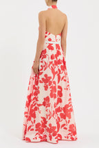 Woman wearing a floral dress with red and white pattern on a plain background