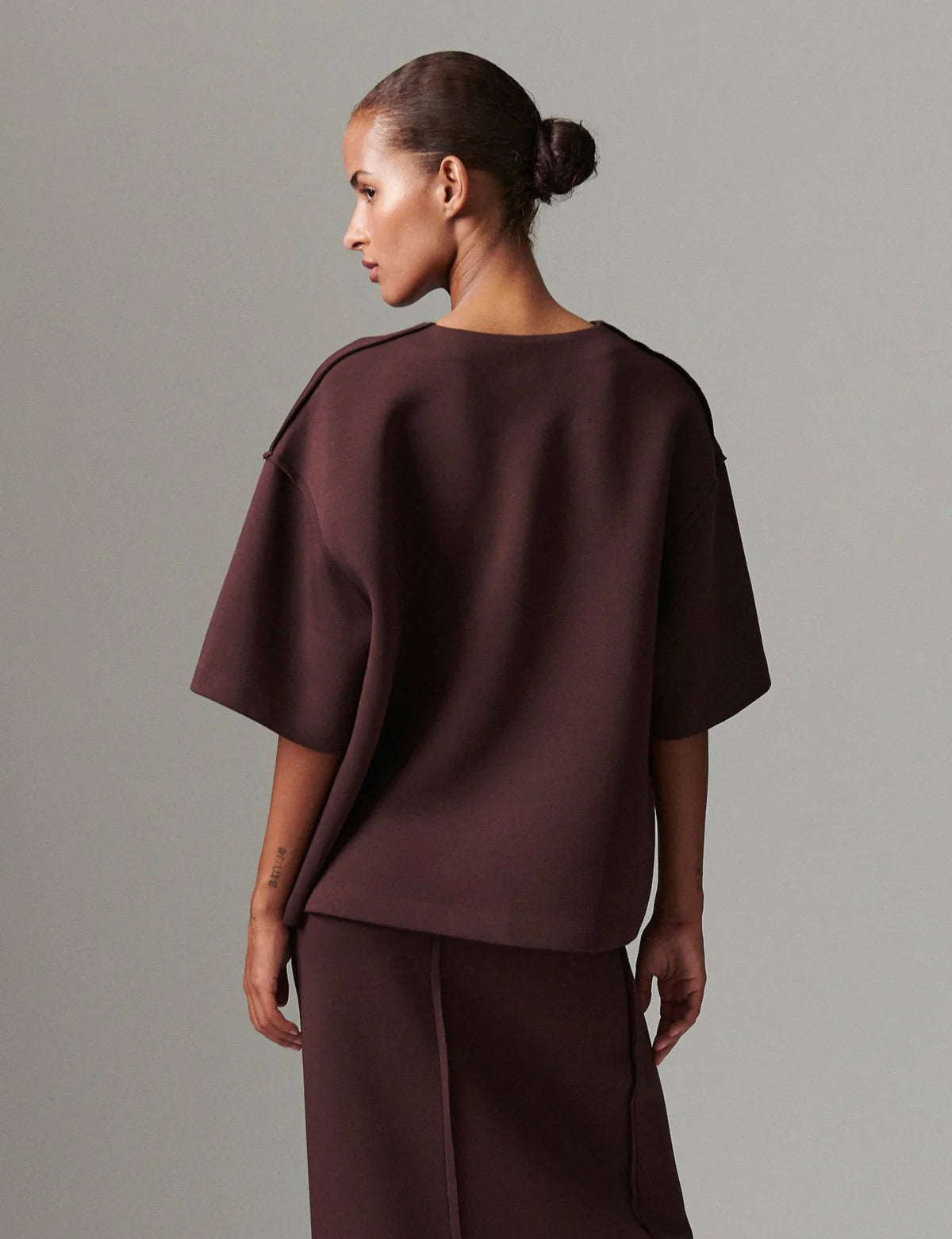 Woman wearing a brown outfit against a gray background