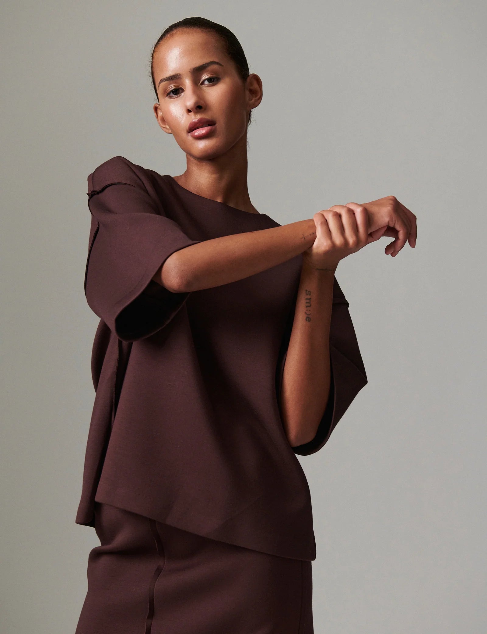 Woman wearing a brown outfit against a plain background