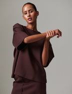 Woman wearing a brown outfit against a plain background