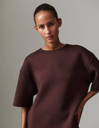 Woman wearing a dark brown oversized t-shirt against a plain background
