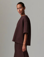 Woman wearing a brown outfit against a plain background