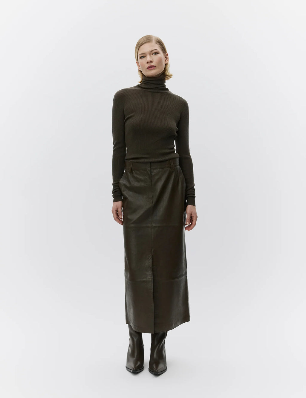 Woman wearing a dark green turtleneck and leather skirt on a white background
