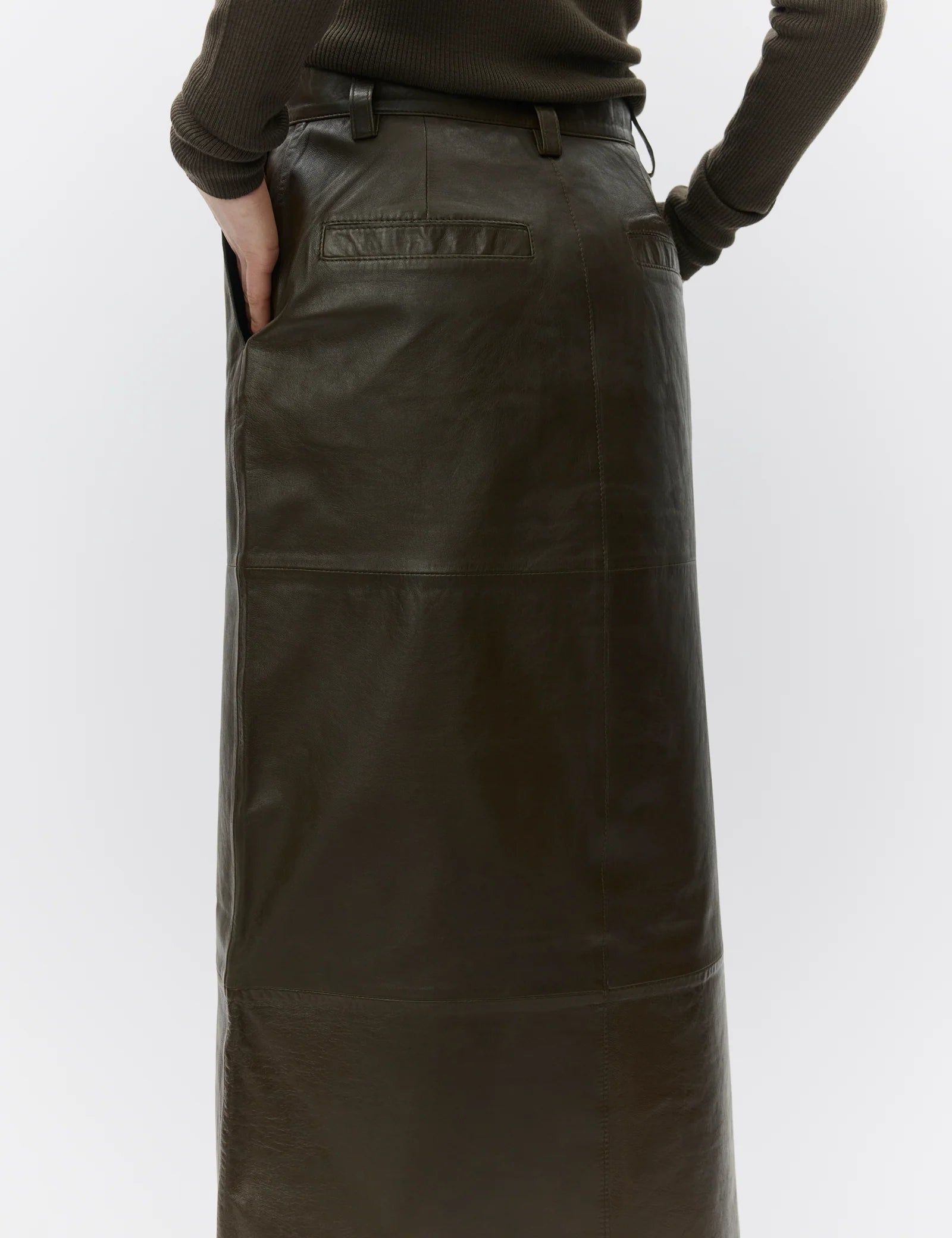 Person wearing a long dark green leather apron on a white background