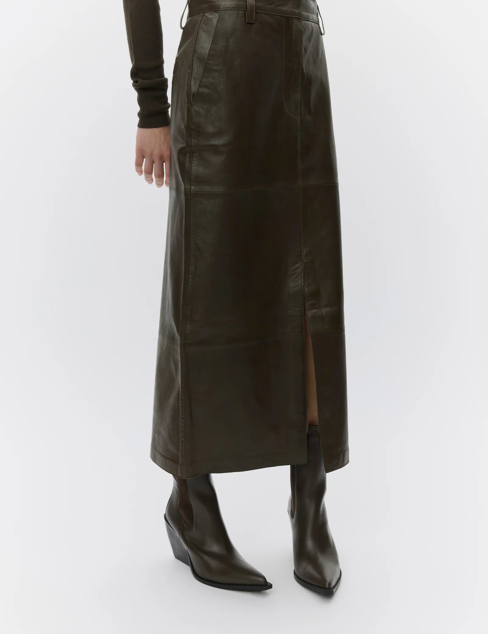 Person wearing a long dark brown leather skirt and black boots on a white background