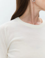 Close-up of a person wearing a white long-sleeve shirt with a plain background