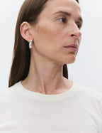 Close-up of a woman wearing silver earrings against a white background