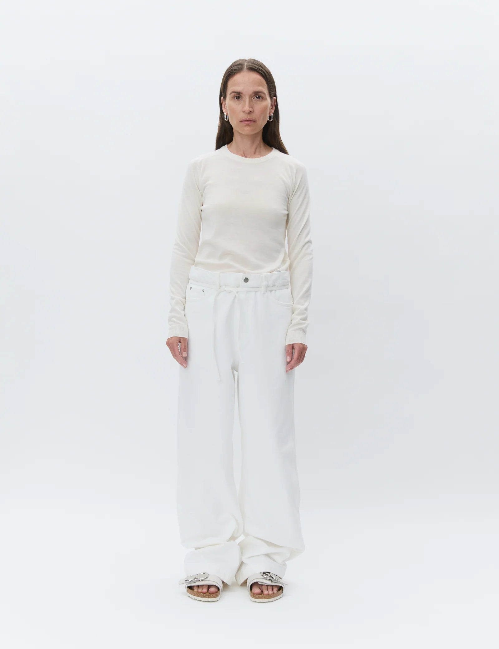 Person wearing a white long-sleeve top and white pants on a white background