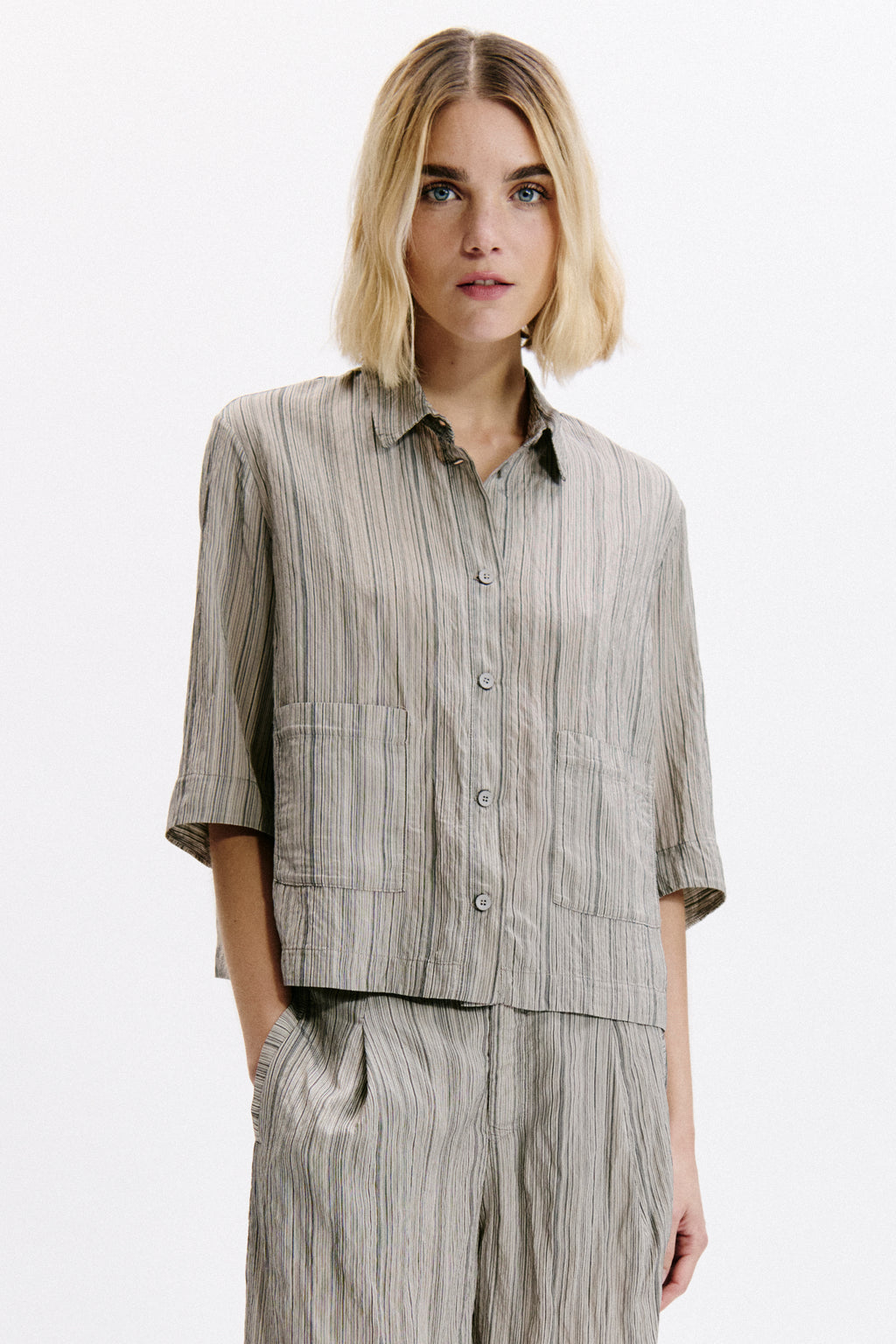 Woman wearing a matching striped shirt and pants set on a white background