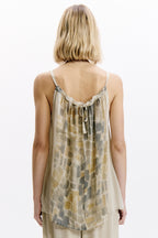 Woman wearing a sleeveless, patterned top on a white background