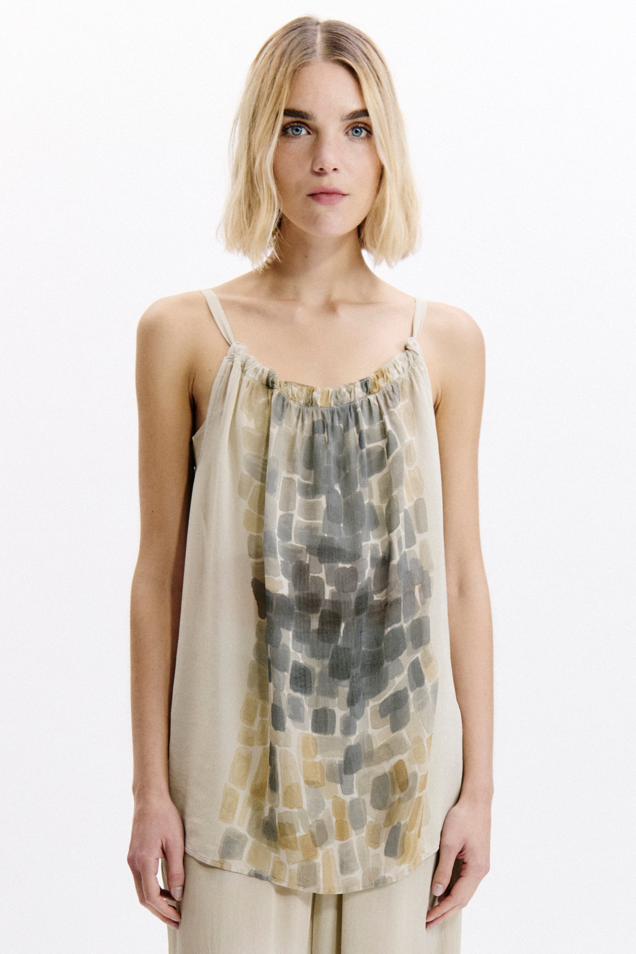 Woman wearing a sleeveless top with a geometric pattern on a white background