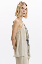 Woman wearing a beige sleeveless top with a patterned side panel on a white background