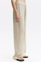 Beige pants worn by a person on a white background