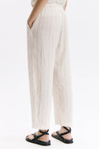 Person wearing white pleated pants on a white background