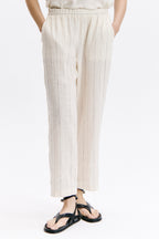 Person wearing white pleated pants on a white background