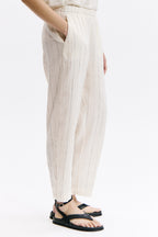 Person wearing striped pants and black sandals on a white background