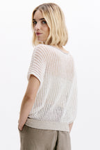 Woman wearing a light-colored knit top against a white background