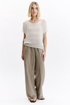 Woman wearing a white checkered top and beige pants on a white background