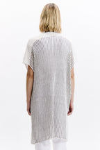 Woman wearing a ribbed knit poncho with a white background