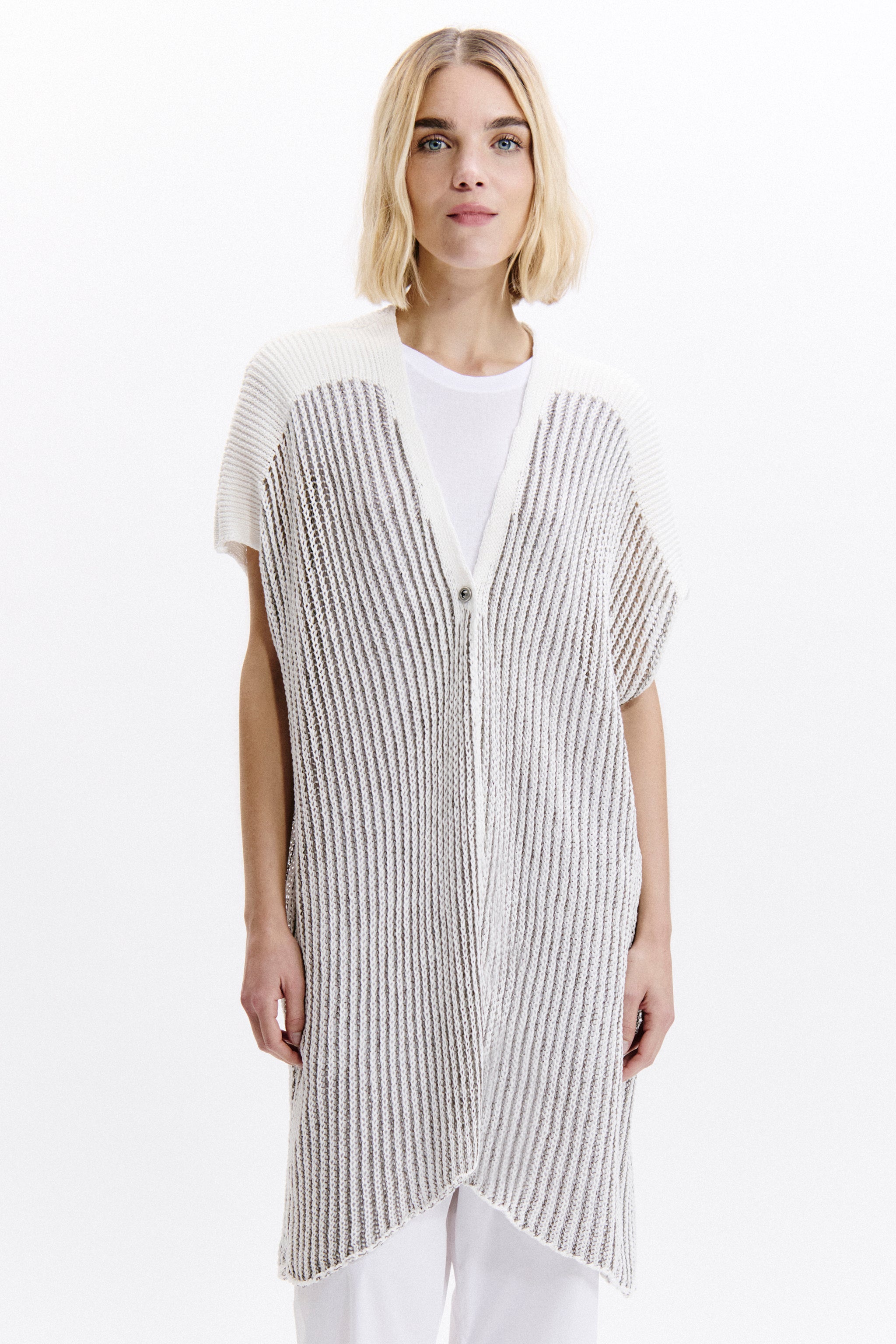 Woman wearing a long, thin striped vest over a white shirt on a white background