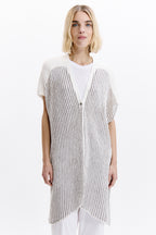 Woman wearing a long, thin striped vest over a white shirt on a white background