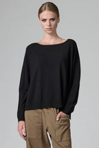 Woman wearing a black top and brown pants on a gray background