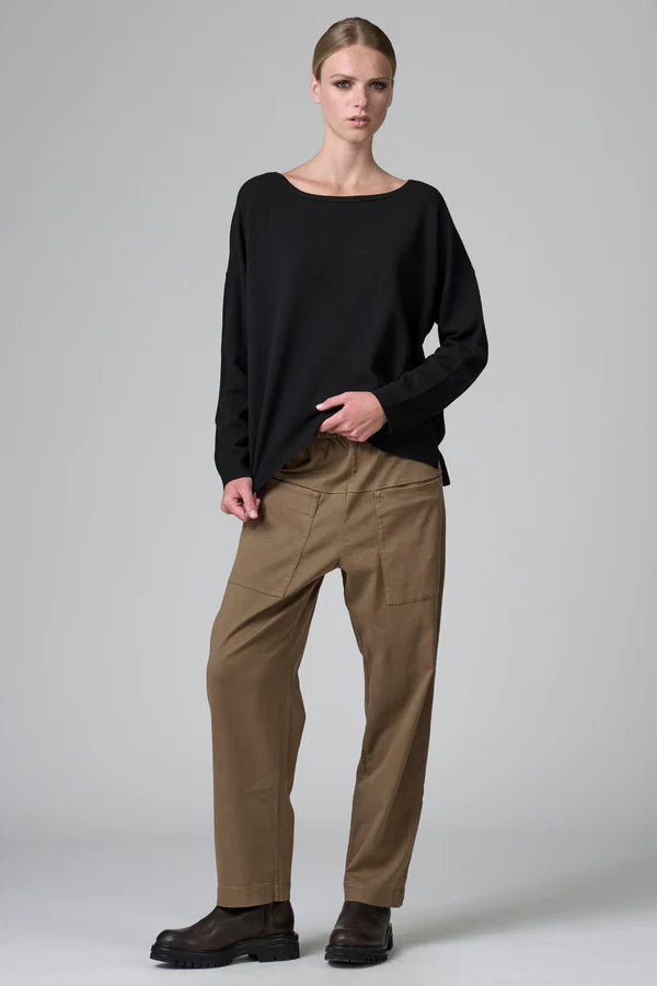 Person wearing a black sweater and beige pants on a gray background