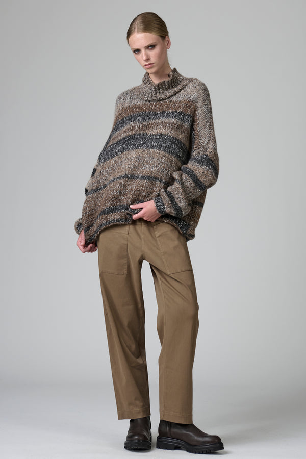 Person wearing a patterned sweater and beige pants on a gray background