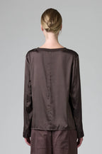 Person wearing a brown satin outfit with a plain background