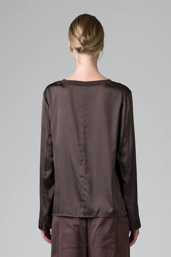 Person wearing a brown satin outfit with a plain background